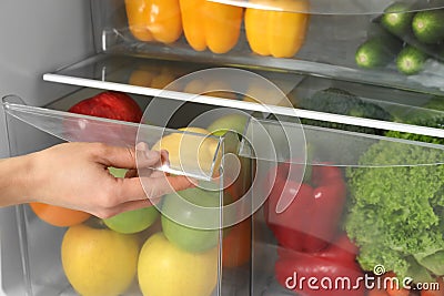 Woman opening refrigerator drawer with fresh fruits Stock Photo