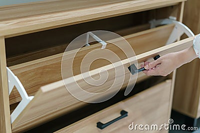 Woman opening wooden shoes storage cabinet for keep her shoes Stock Photo