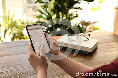 Woman ordering taxi with smartphone at table, closeup Stock Photo