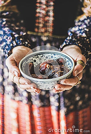 Woman in oriental dress holding bowl of dates for Ramazan Stock Photo