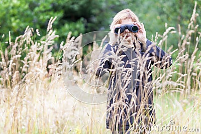 Woman ornithologist studying birds with binocular, vanished out of sight in high grass Stock Photo