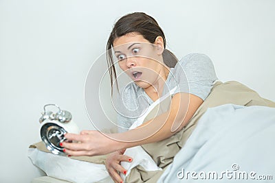 woman oversleeping and realising time on alarmclock Stock Photo