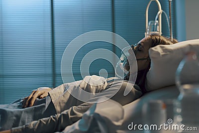 Woman with oxygen mask lying in a hospital bed Stock Photo