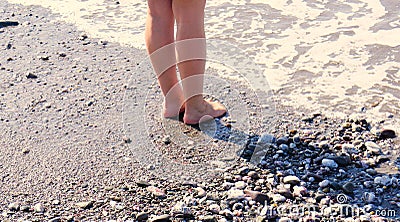 At the edge of the sea, woman`s feet/legs with the sea gently lapping them Stock Photo