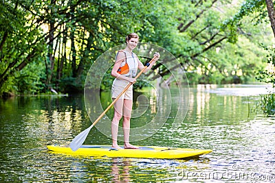 Woman paddling with surfboard sup on forest river Stock Photo