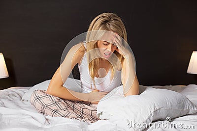 Woman in pain sitting in bed Stock Photo