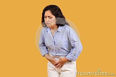 Woman with a pained expression, clutching her abdomen, possibly experiencing stomach pain Stock Photo
