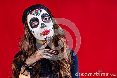 woman with painted skull on her face for Mexico D a de Muertos Mexican traditional ritual in red studio background Stock Photo