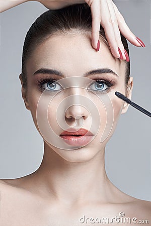 Woman paints eyes and eyelashes brush for eyelashes. Increase in volume of eyelashes, cosmetics for eye care. Beautiful female Stock Photo