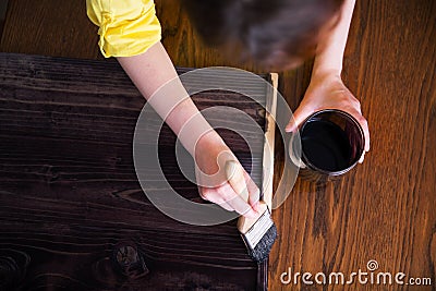 A woman paints planks with a stain of ebony wood stain. Stock Photo