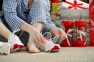 Woman in pajamas ties the laces of athletic shoes. Stock Photo