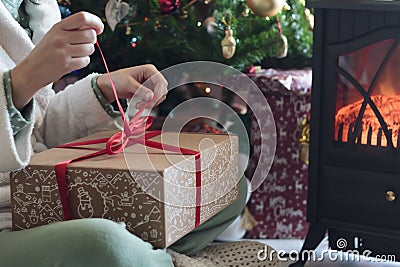Woman in pajamas unwrapping gift box on Christmas morning Stock Photo