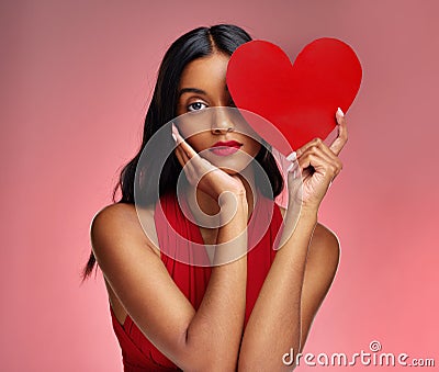 Woman, paper heart and face in studio portrait for makeup, beauty or romantic sign by red background. Girl, fashion Stock Photo
