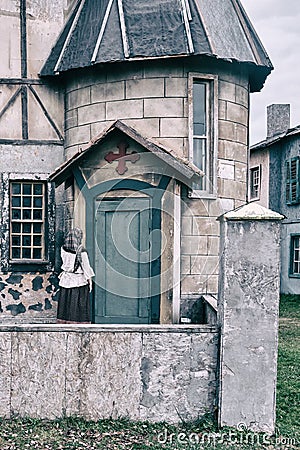 A girl parishioner in a headscarf is facing the door of a vintage Church Stock Photo