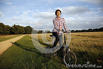 Woman in the park cycling Stock Photo