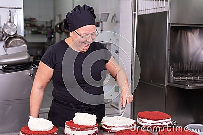 Woman pastry chef smiling and working happy, making cakes at the pastry shop. Stock Photo