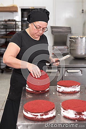 Woman pastry chef smiling and working happy, making cakes at the pastry shop. Stock Photo