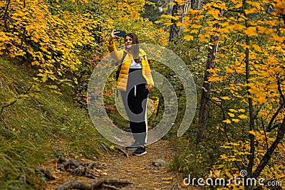 Woman path autumn forest. A young dark-haired woman in a yellow-black suit Stock Photo