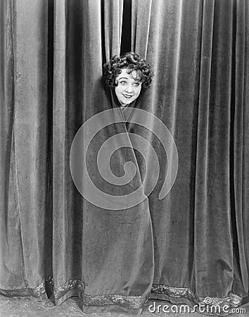 Woman peek-a-booing behind a curtain Stock Photo