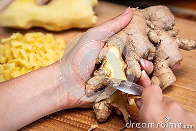 Woman is peeling ginger with a teaspoon, chopped bites in the back Stock Photo