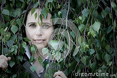 Woman peering through leaves Stock Photo