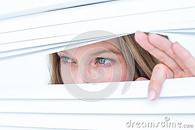 Woman peering through roller blind Stock Photo