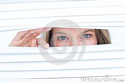 Woman peering through roller blind Stock Photo