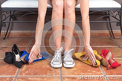 Woman with perfect slim legs, choosing comfortable sneakers rather than uncomfortable high heels shoes. Stock Photo
