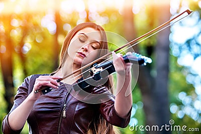 Woman perform music on violin park outdoor. Girl performing jazz . Stock Photo