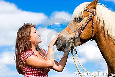 Woman petting horse on pony farm Stock Photo