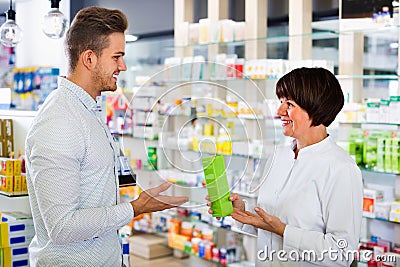 Woman pharmacist helping customers in drug store Stock Photo