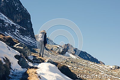 A woman photographer with camera and backpack in a winter jacket with fur stands on the snow mountain in Switzerland. Fluela pass Stock Photo