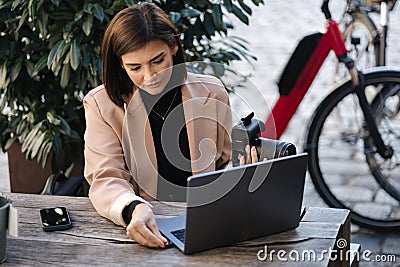 Woman photographer put memory card in laptop. Female freelancer copy files. Professional content maker working in cafe Stock Photo