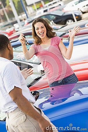 Woman picking up keys to new car Stock Photo