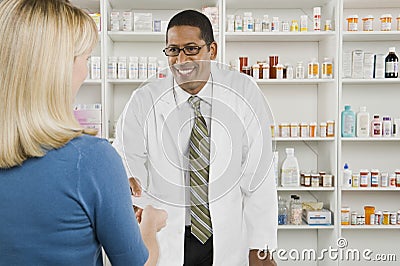 Woman Picking Up Prescription Drugs At Pharmacy Stock Photo