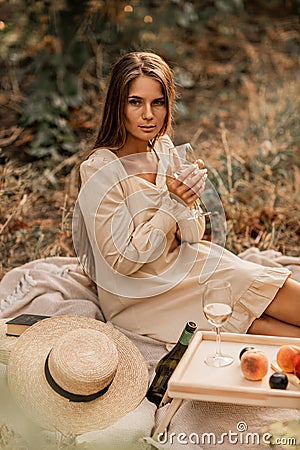 Woman picnic vineyard. Romantic dinner, fruit and wine. Happy woman with a glass of wine at a picnic in the vineyard on Stock Photo