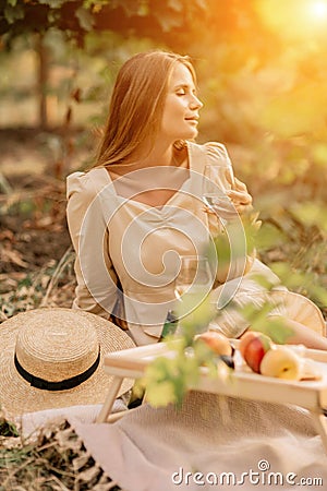 Woman picnic vineyard. Romantic dinner, fruit and wine. Happy woman with a glass of wine at a picnic in the vineyard on Stock Photo