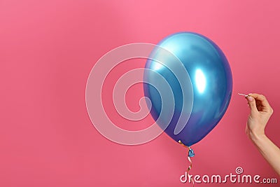 Woman piercing balloon with needle on color background, closeup. Stock Photo