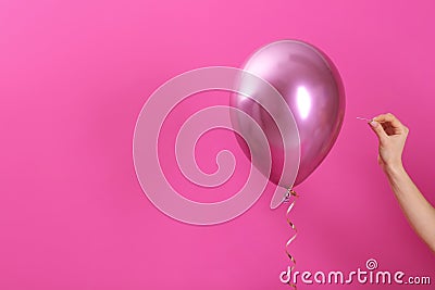 Woman piercing balloon with needle on color background, closeup. Stock Photo