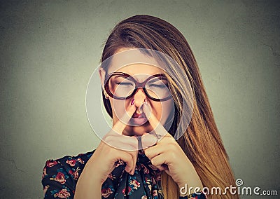 Woman pinches nose with fingers looks with disgust bad smell Stock Photo