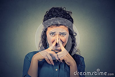 Woman pinches nose with fingers looks with disgust something stinks bad smell Stock Photo