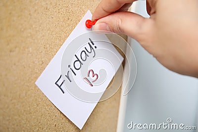 Woman pinning paper note with phrase Friday! 13 to cork board. Bad luck superstition Stock Photo
