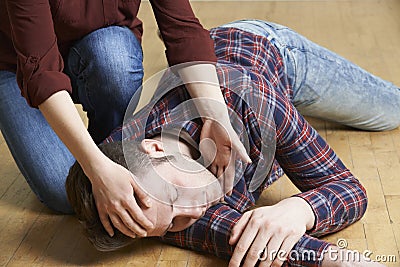 Woman Placing Man In Recovery Position After Accident Stock Photo