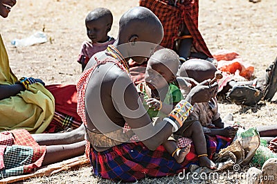 Masai Woman playing with baby , People of Maasai Tribe sitting on ground, Tanzania, Africa Editorial Stock Photo