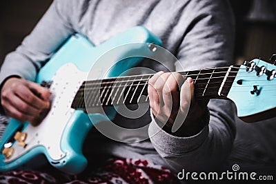 Woman playing blue electric guitar close up at home. Practicing guitar Stock Photo