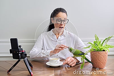 Woman playing with her pet parrot at home, bird biting woman& x27;s finger Stock Photo