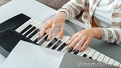 Woman playing piano record music on synthesizer using notes and laptop. Female hands musician pianist improves skills Stock Photo