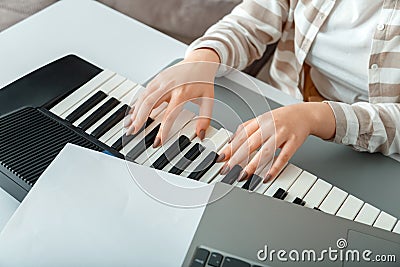 Woman playing piano record music on synthesizer using notes and laptop. Female hands musician pianist improves skills playing Stock Photo