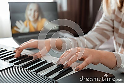 Woman playing piano during video call via laptop. Female hands musician pianist improves skills playing piano online classes with Stock Photo