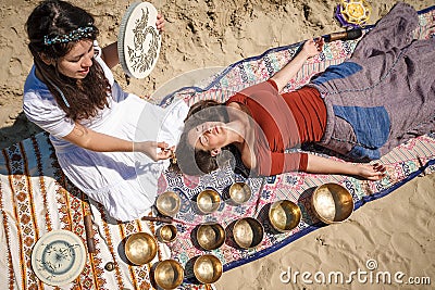 Woman playing a singing bowls also known as Tibetan Singing Bowls, Himalayan bowls. Making sound massage. Stock Photo